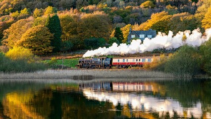 Beautiful shot of a train traveling across a mountain range seen through tranquil waters