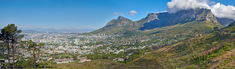 Naklejka premium Panoramic landscape view of the majestic Table Mountain and city of Cape Town in South Africa. Beautiful scenery of a popular tourist destination and national landmark with cloudy blue sky copy space