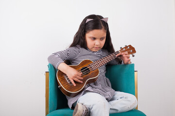 Picture of girl playing ukulele with light background. Concept of music and hobbies.