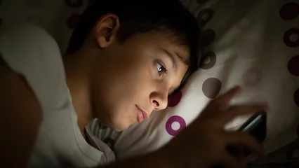 Foto op Plexiglas Child inside social networks with his smartphone from bed at night before sleeping. Concept of kids using social networks and their dangers without parental control at night from their room © Pixel_Studio_8