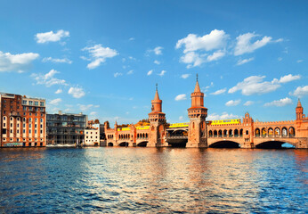 Fototapeta premium A bridge over a river with a building in the background. Oberbaumbrucke in Berlin on a bright sunny day