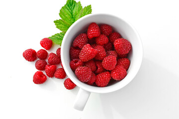 maliny  w białym kubku, czerwone maliny,  maliny z zielonym listkiem, fresh raspberries in a cup, red raspberries, juicy raspberries with a green leaf, Rubus idaeus, rasberry view from above,białe tło