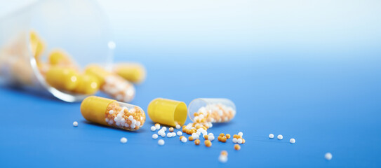 Pills spilling out of a bottle on a blue surface. Copyspace, place for text. - obrazy, fototapety, plakaty