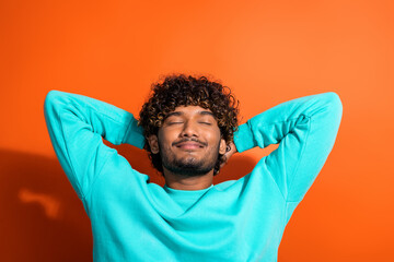 Portrait of satisfied positive person closed eyes hands behind head enjoy free time isolated on orange color background