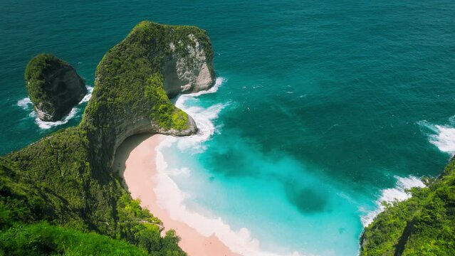 Kelingking beach with clear Indian Ocean waves crashing on amazing pink sandy shore in Bali.