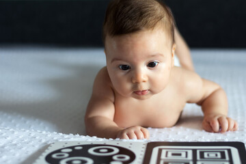 A baby looks at a black and white contrast educational book. Intellectual development of newborns....