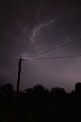 Electric pole with Thunderstorm Overhead. NIght photography of thunder with lightnings.