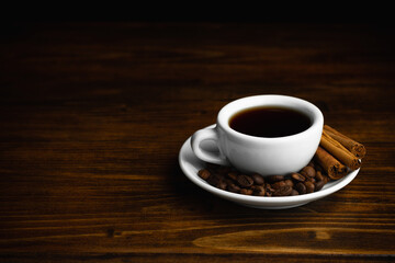 Fototapeta na wymiar A cup of aromatic black coffee. Morning espresso or Americano coffee for breakfast in a beautiful cup. Cinnamon sticks. Wooden background.