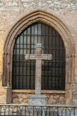 Fototapeta premium Medieval stone cross infront of the window of a church.