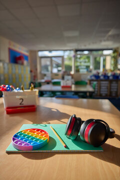 Ear Defenders Or Headphones And Fidget Toy To Help Child With ASD Or Autism On Table In School Classroom