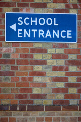 Fototapeta na wymiar School Entrance Sign On Brick Wall Of School Building