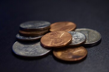 Pile of different coins of various sizes on a flat gray surface