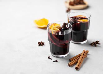 Mulled wine with orange, apple  and cinnamon in glasses on a light background. The concept of a traditional winter hot drink with spices and fruits.