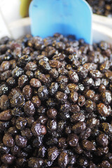 slices black olives with spoon in a bowl ,