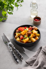 Fried pork meat with potatoes, onions and peppers. National homemade Georgian dish ojakhuri in a black bowl on a light background