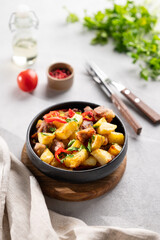 Fried pork meat with potatoes, onions and peppers. National homemade Georgian dish ojakhuri in a black bowl on a light background