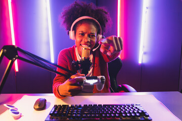 Host channel of gaming streamer, African girl playing online game with joystick, talking with...
