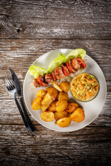 Shish kebab served with roasted potatoes and salad.