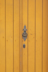 Old yellow door with wrought iron knocker