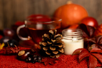 Autumn composition. A pinecone, a candle and tea on the table. Ingathering