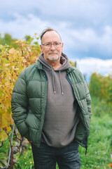 Outdoor portrait of middle age 55 - 60 year old man enjoing nice autumn day in vineyards, healthy and active lifestyle - 672395235