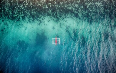 Aerial view of white and red bankga boat in blue and turquoise sea by the algal shore - obrazy, fototapety, plakaty