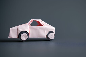 pink origami style car on a gray background with black wheels