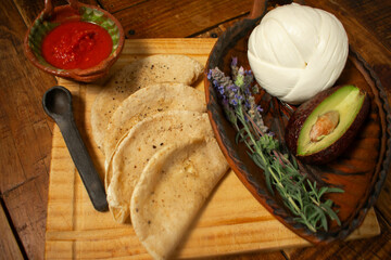 Toma cenital de unas quesadillas sobre una tabla de madera promocionando el queso oaxaca blanco 