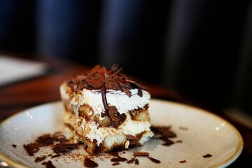 White plate with Tiramisu dessert topped with chocolate shavings