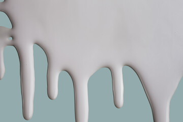 White cream milk emulsion liquid flows in drops blue background