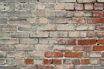 Weathered brick wall with a textured surface and cracks visible on the surface.