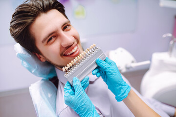 Smiling young man in the dentist's chair. A man in dentistry during a dental procedure. Healthy smile. Review of dental caries prevention.