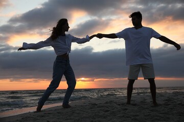 Fototapeta premium Happy couple dancing on beach at sunset