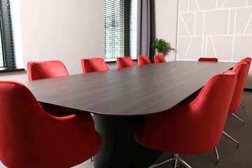 Empty conference room with stylish red office chairs and large wooden table