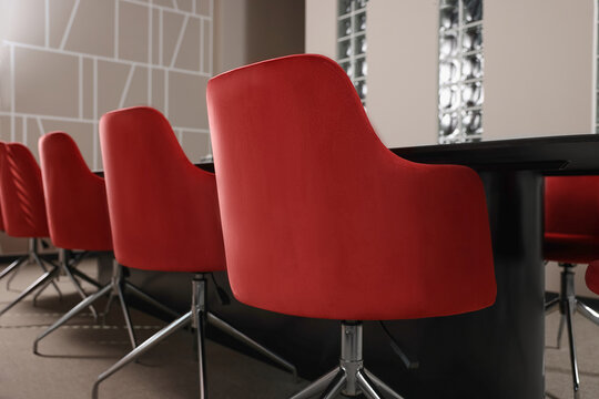 Stylish red office chairs and large table in empty conference room