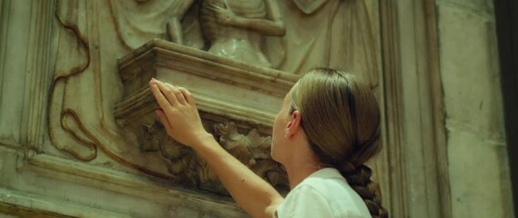 Woman hand touch ancient wall ruins, historical architecture of cathedral church. Close-up of religious girl. Study of art.