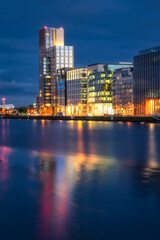 Fototapeta na wymiar Modern offices and apartment buildings on Sir John Rogerson Quay, docklands, reflected in blurred Liffey River at dusk, blue hour, Dublin, Ireland