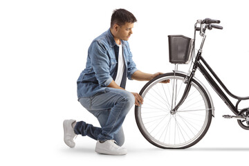 Young man kneeling and looking at a bicycle flat tire