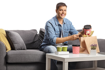 Young man sitting on a sofa with takeaway food boxes