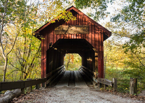 Bean Blossom Covered Bridge at sunset, late fall. Bean Blossom, Indiana. Brown County. Sunlight spotlighting lettering on bridge.