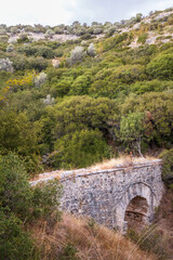 Fototapeta na wymiar Old Kavala nature hiking trail, ancient stone bridge into the woods, Greece