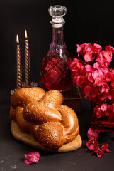 Challah bread, shabbat wine, flowers bugenvil and candles on dark background. Traditional Jewish Shabbat ritual. Shabbat Shalom.