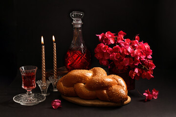 Challah bread, shabbat wine, flowers bugenvil and candles on dark background. Traditional Jewish...
