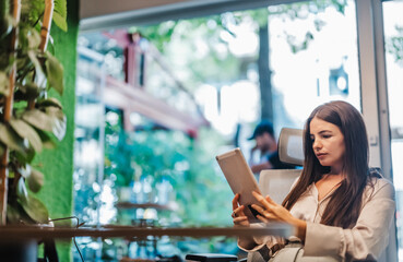 Fototapeta premium Experienced young adult worker gathers data for market research in a modern city center office. Confident and productive, she develop successful strategies for growth and profit in a sunny office.