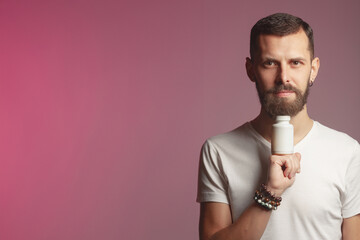 Super supplement concept. Portrait of a young handsome active guy with a white plastic bottle...