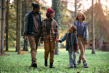 Happy black family talking while enjoying in day in woods.