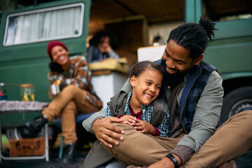 Happy black girl and her father enjoy during family camping day in nature.