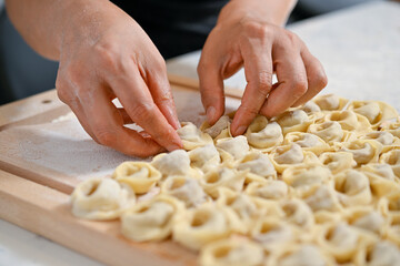 Female hands filling dough with minced meat to prepare Turkish dumpling called manti   