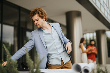Diverse architects, engineers, and designers collaborate outdoors on a construction project. They inspect blueprints, discuss ideas, and promote teamwork for profitable and innovative project work.