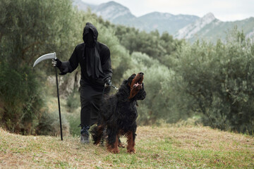 Hooded Person with Dog, Mysterious cloaked figure stands in a natural setting, holding a scythe, accompanied by a Gordon Setter dog barking